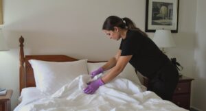 A woman in purple gloves is cleaning a bed